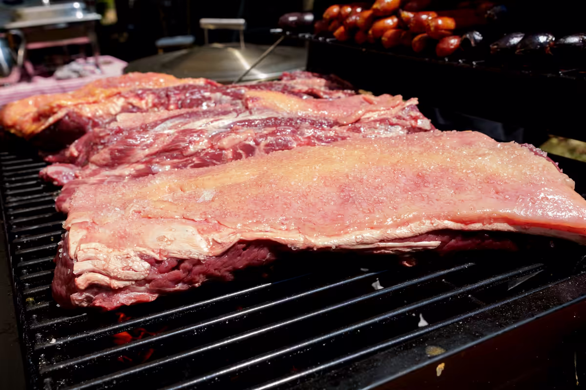 Costillas y cortes de carne asándose sobre la parrilla