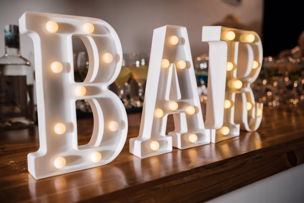 Letras luminosas que forman la palabra BAR sobre la barra de bebidas