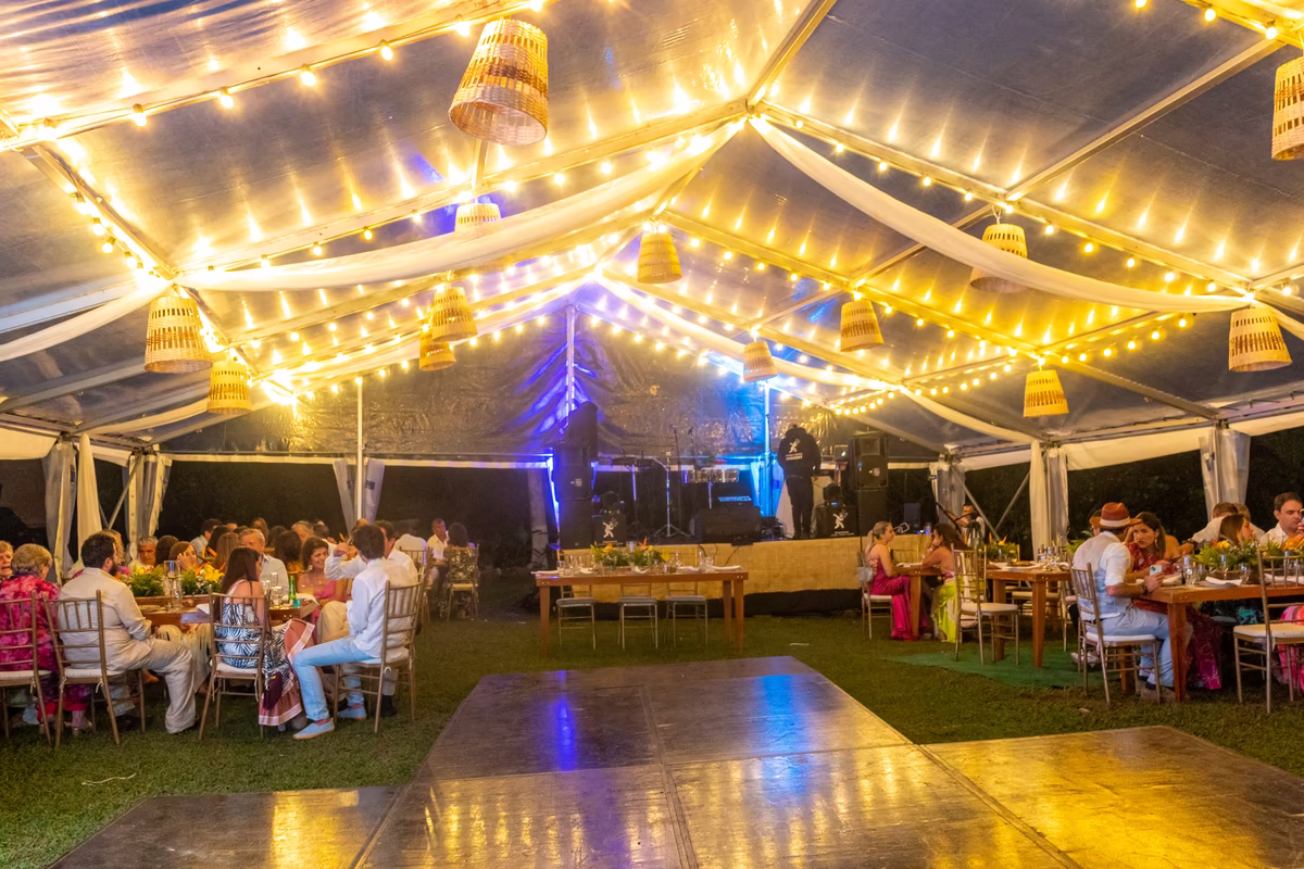 Carpa con guirnaldas de luces, pista de baile y los invitados en las mesas