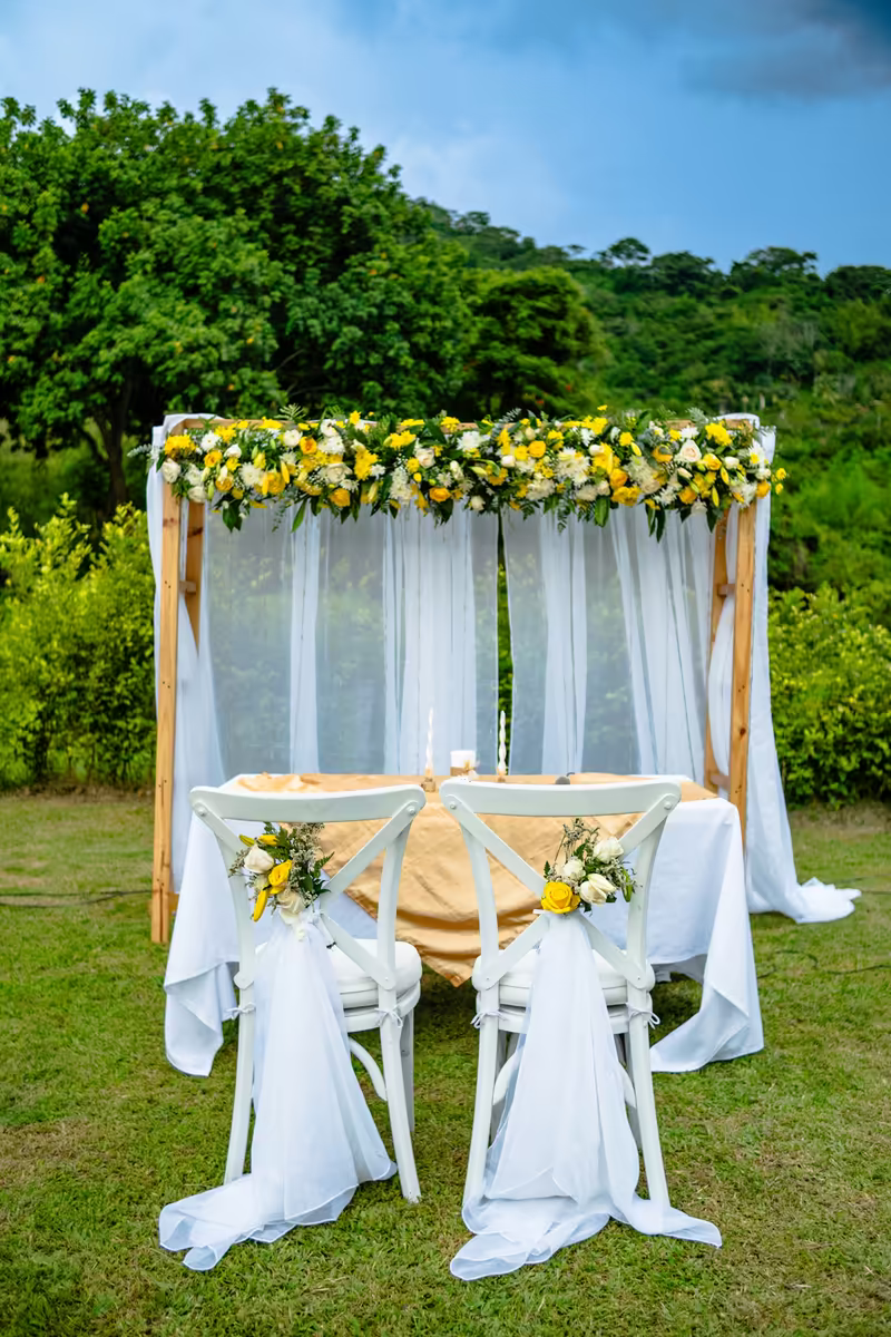Altar de ceremonia con cortinas blancas y flores amarillas y blancas