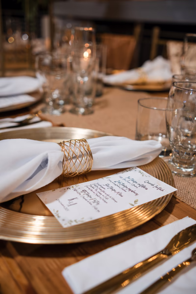 Puesto de mesa con bajoplato dorado, servilleta con anillo y el menú escrito a mano