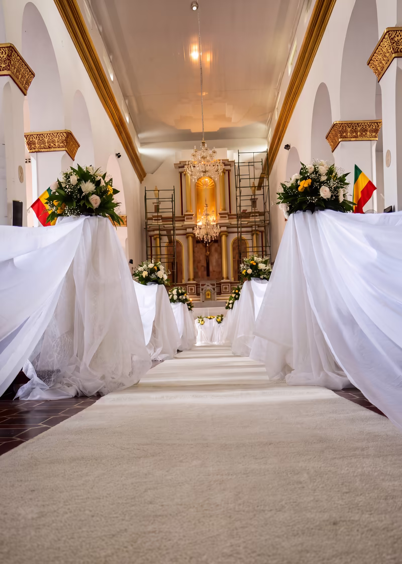 Detalle del camino de la iglesia, con las bancas vestidas de blanco y arreglos florales