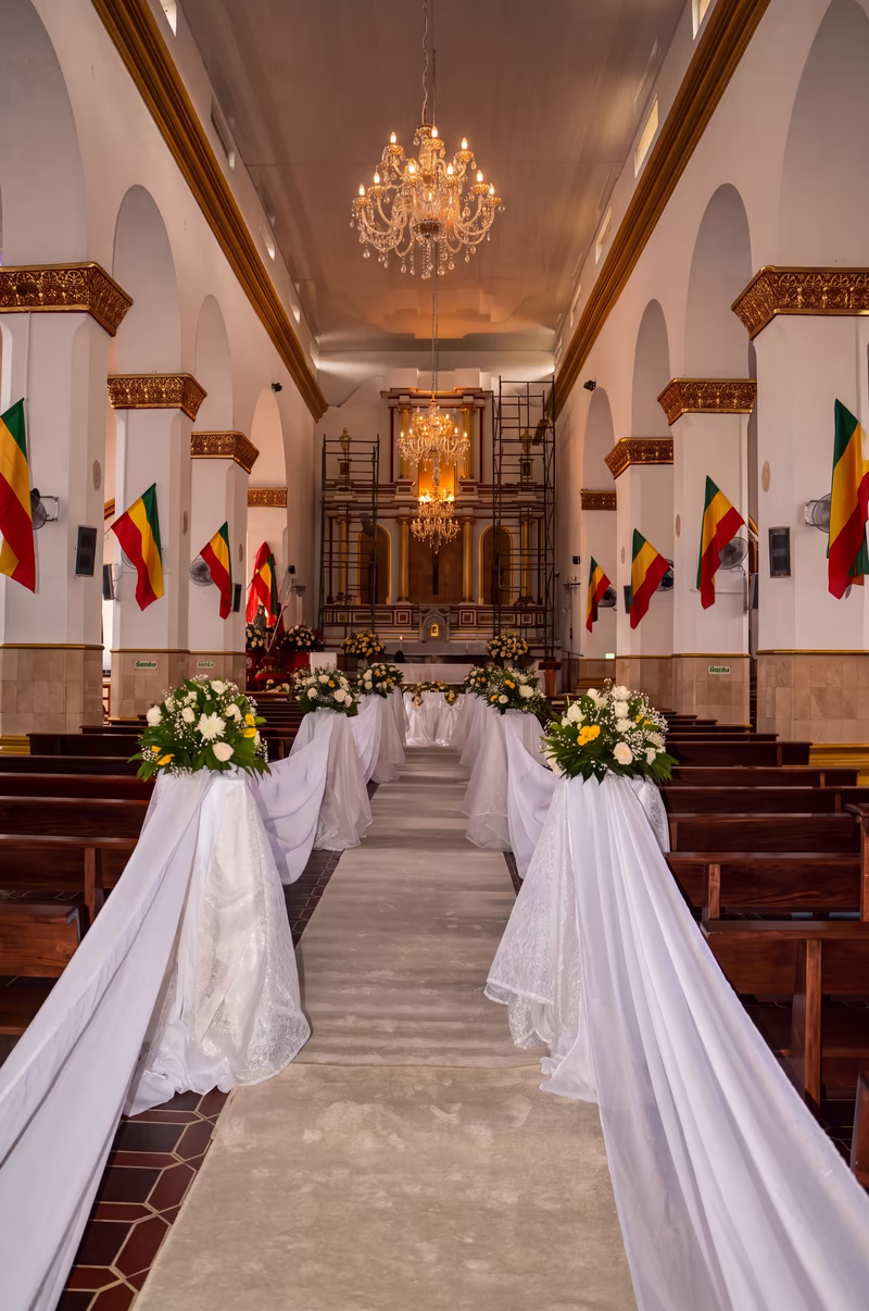 Camino central de la iglesia con alfombra, telas blancas en las bancas y el altar al fondo