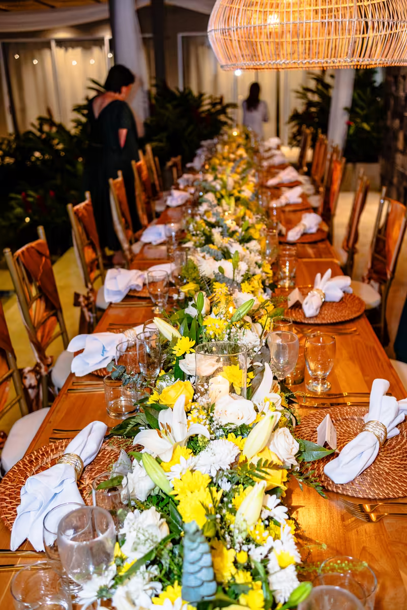 Salón interior con mesas largas y arreglos florales blancos altos