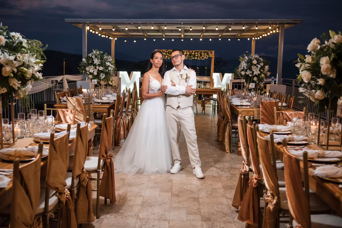 Novios en el salón de recepción montado con luces colgantes y sillas decoradas