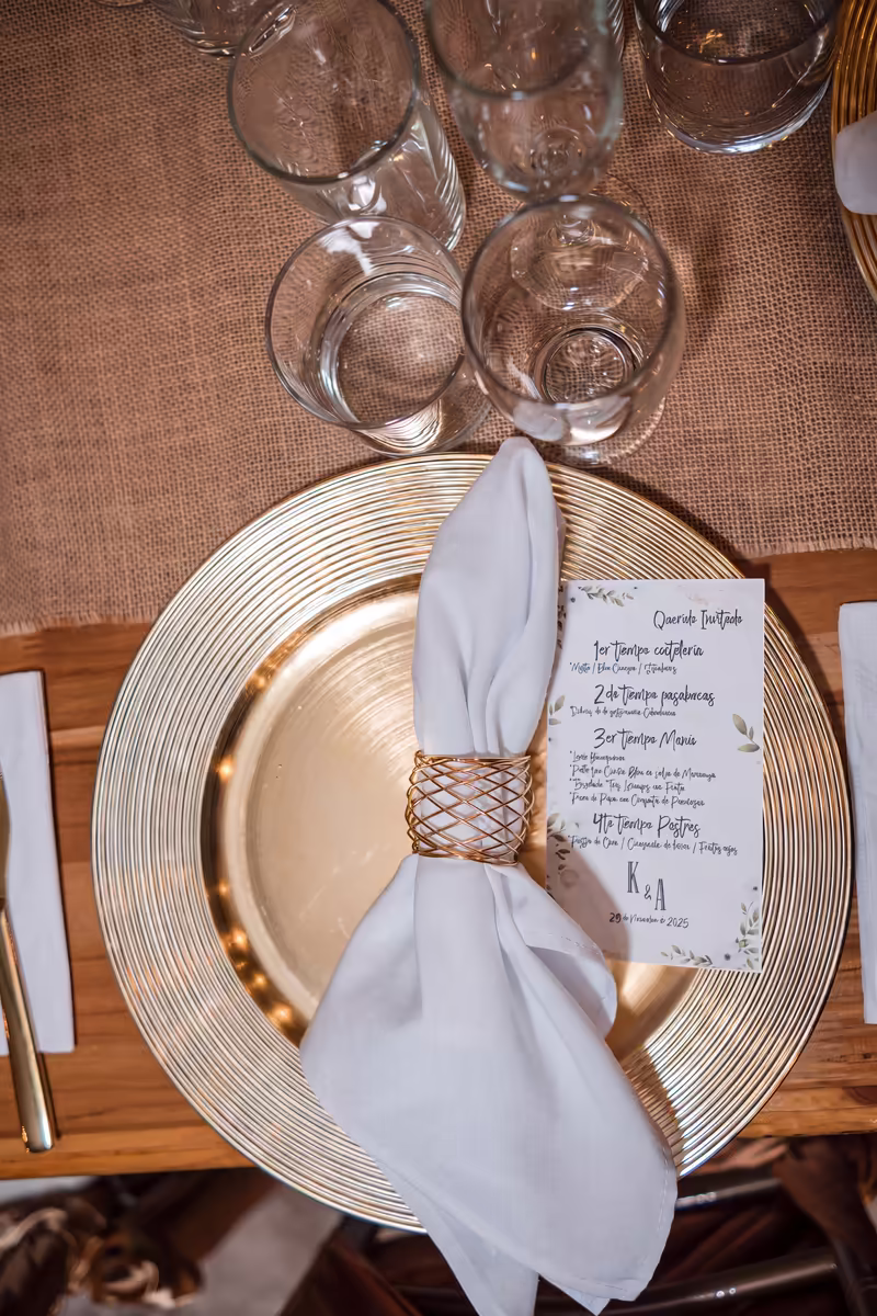 Puesto de mesa con plato dorado, servilleta y el menú impreso del evento