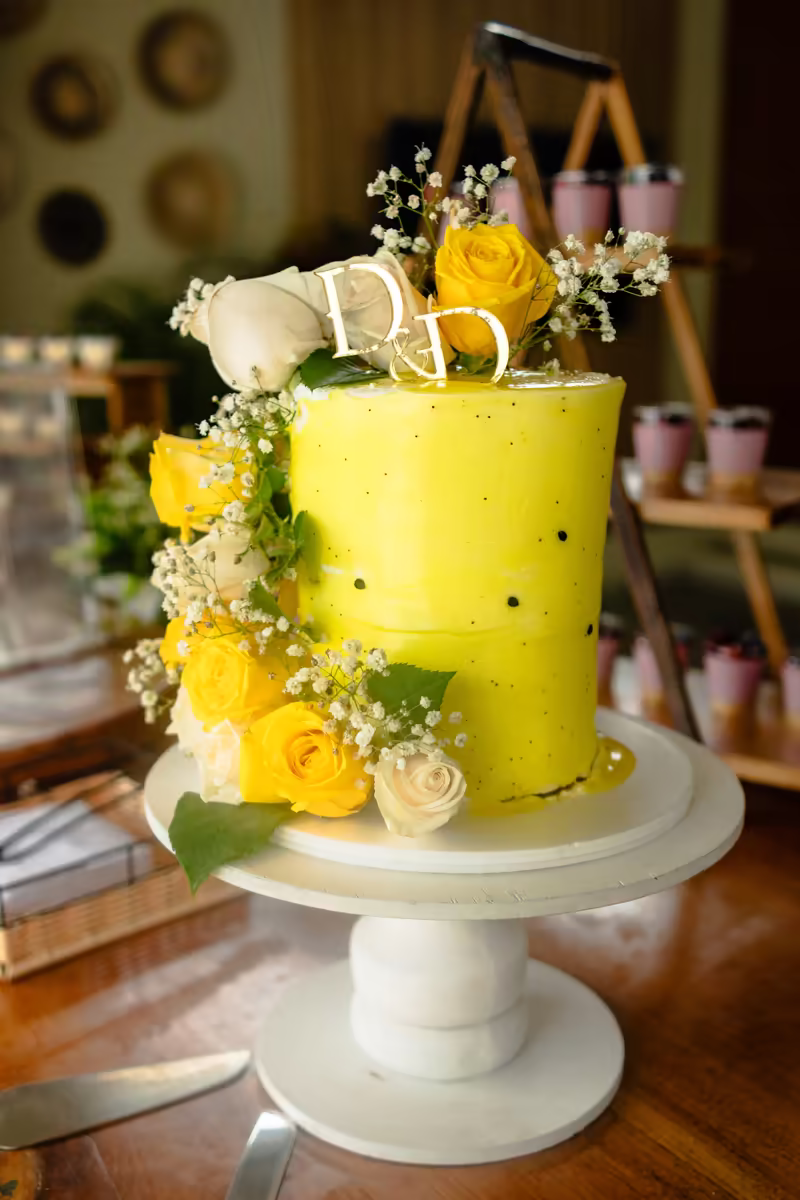 Torta de dos pisos en amarillo decorada con rosas y flores naturales