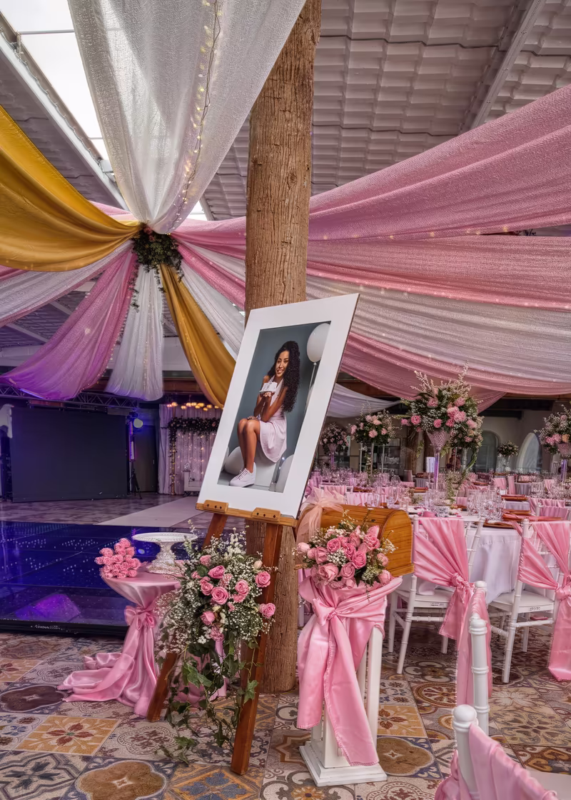 Retrato de la quinceañera sobre un caballete, entre las telas rosadas y doradas del salón