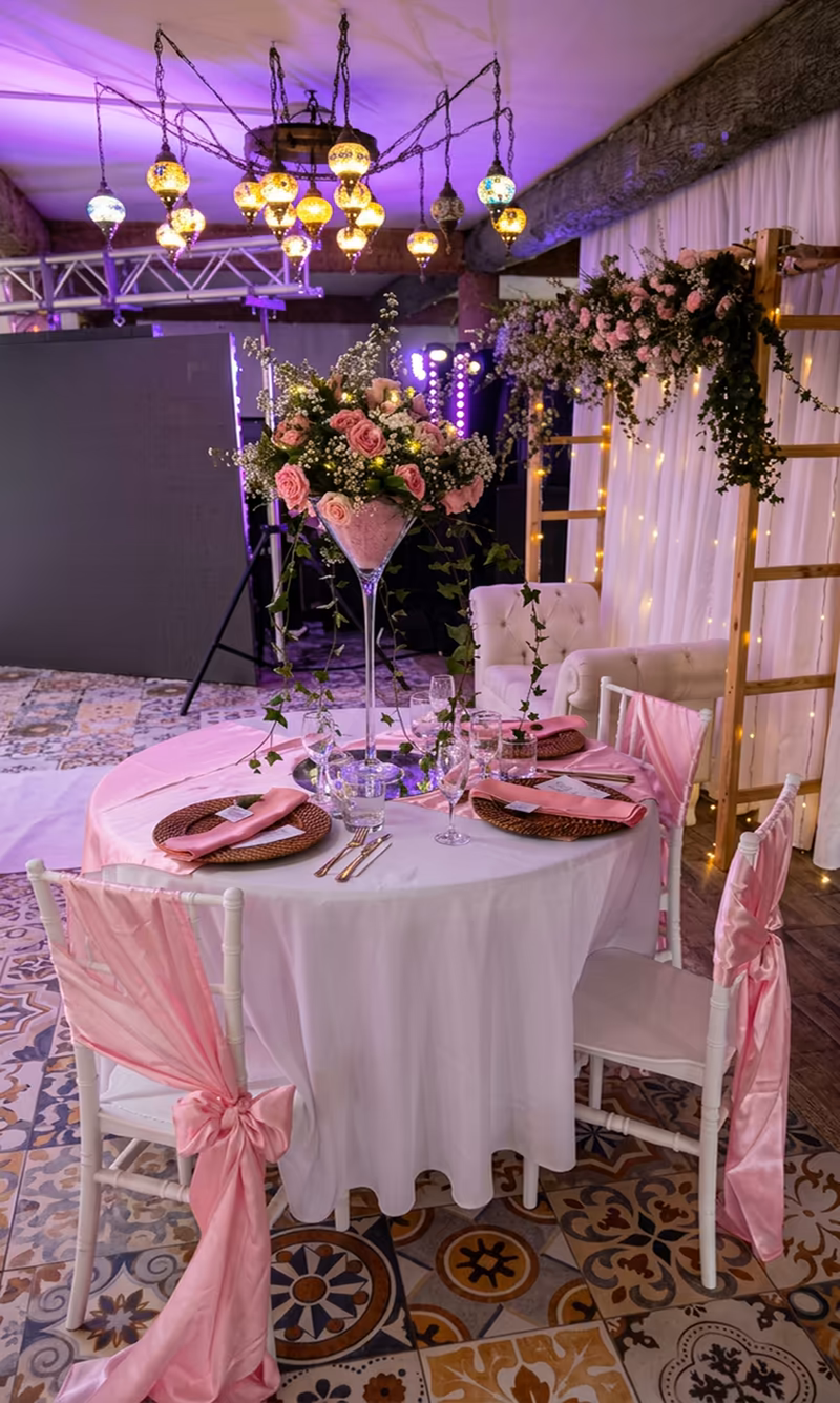Mesa con copa gigante de flores y escalera decorada, junto a la lámpara del salón