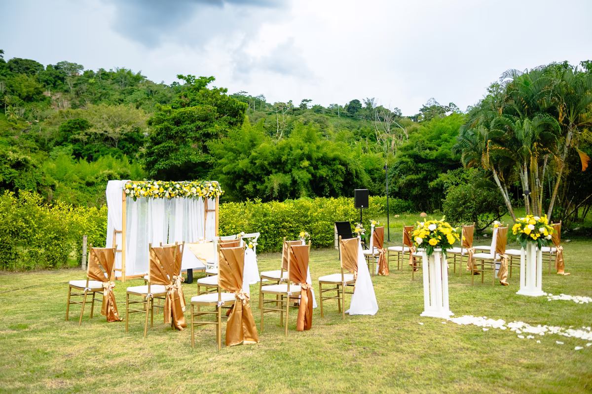 Ceremonia al aire libre con el altar vestido de flores amarillas y las sillas con lazos dorados