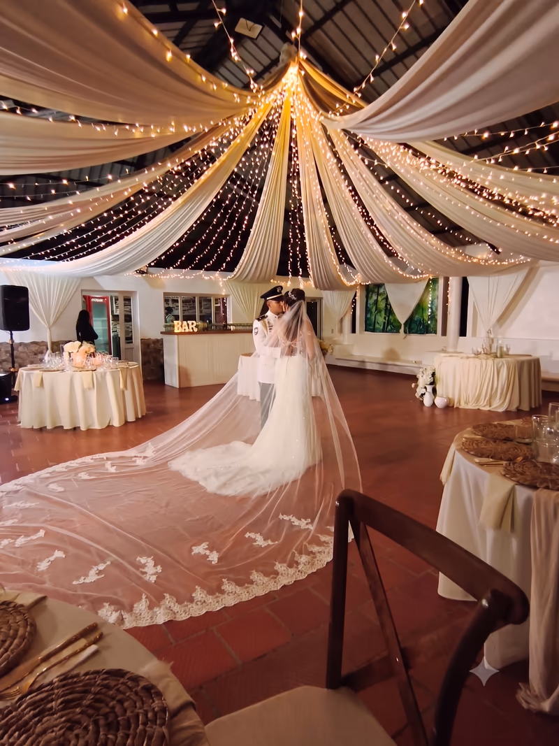 La novia con el velo extendido en el salón decorado con telas y luces cálidas